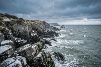 Côte sauvage du Finistère en hiver avec rochers granitiques et mer agitée sous ciel nuageux
