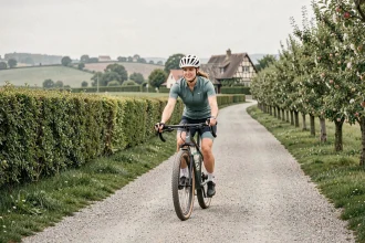 Cycliste femme sur une voie verte normande bordée de pommiers en fleurs et de haies bocagères