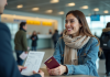 Modifier le nom sur un billet d’avion : comment faire et dĂ©marches Ă suivre Jeune femme Ă l'aĂ©roport lors de l'enregistrement