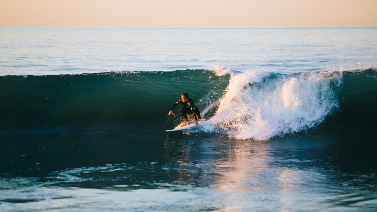 jeune homme pratiquant le surf et se trouvant sur une vague