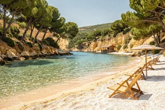 Plage sauvage de Rayol-Canadel avec eau turquoise, parasols en bois et paillote de plage entourée de pins maritimes